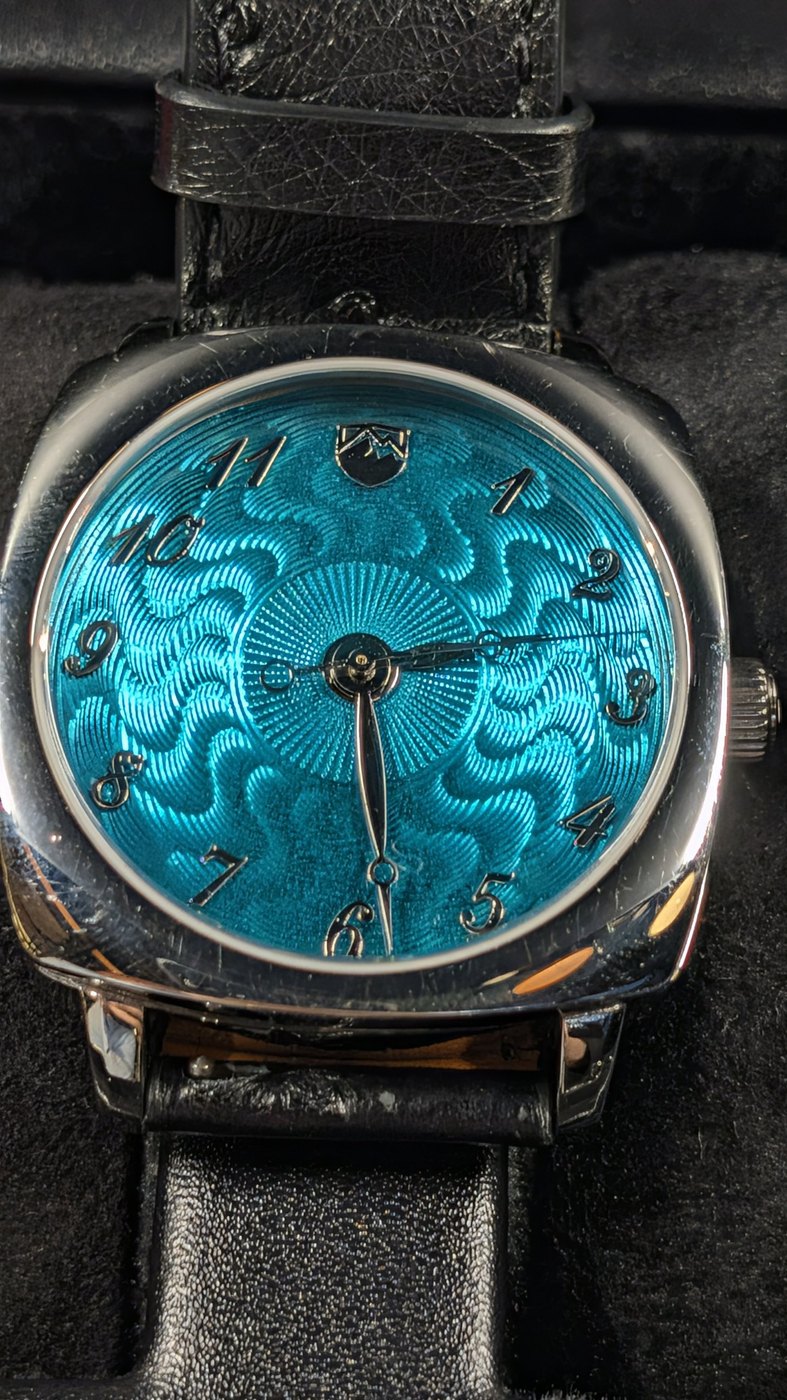A cushion-cased watch with a turquoise guilloché enamel dial, photographed inside Model D.