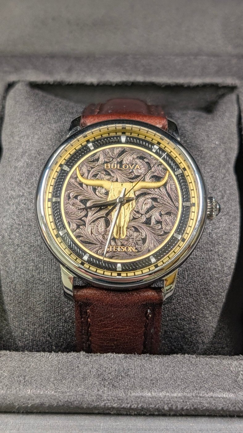 A watch with an engraved floral dial and gold longhorn skull, photographed inside Model D.