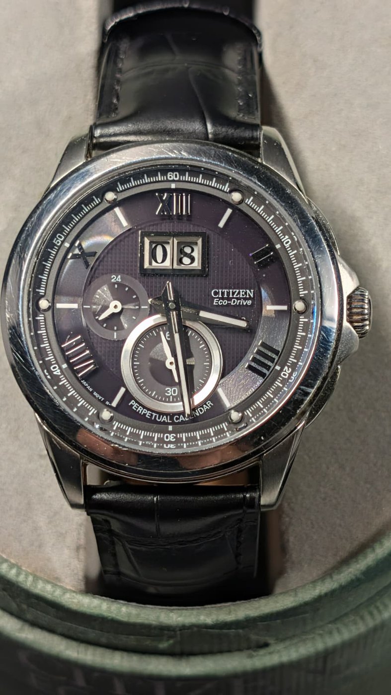 A perpetual calendar watch with a dark dial and big date window, photographed in an earlier Model D prototype.