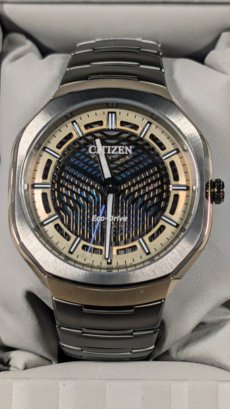A steel watch with an openworked blue and silver dial on a bracelet, photographed in an earlier Model D prototype.